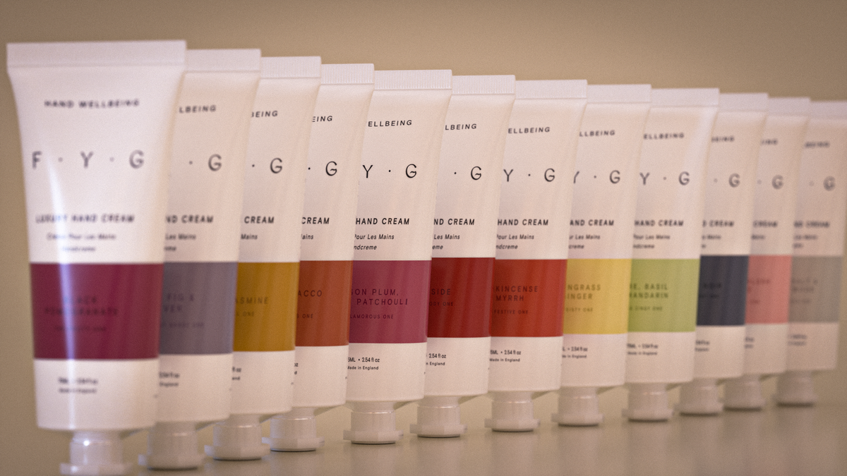 Row of F.Y.G hand cream tubes in various colors on a neutral background
