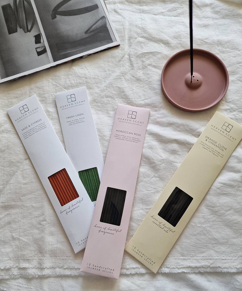 Four incense stick packages on a textured surface with a pink incense holder.
