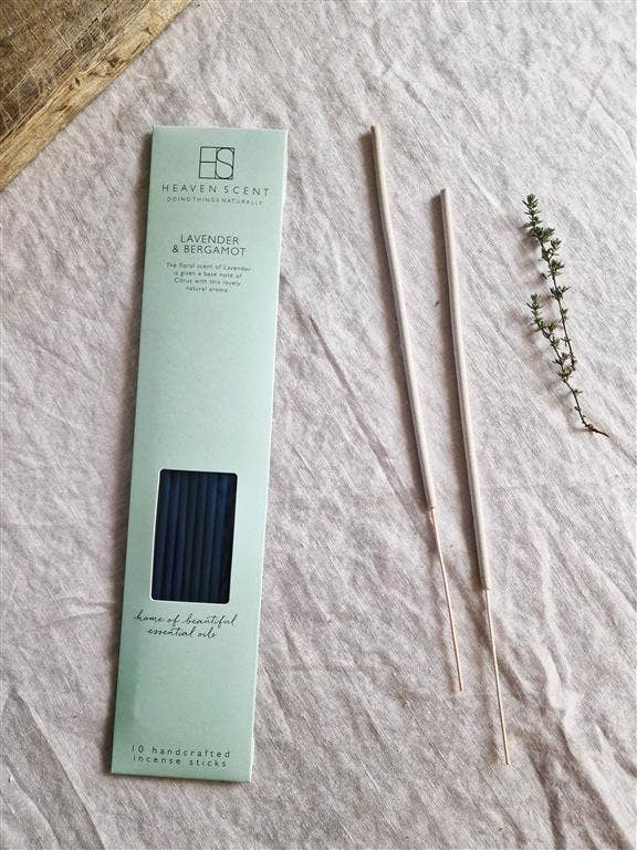 Heaven Scent Lavender & Bergamot incense sticks in their mint green packaging, displayed on a textured light beige linen fabric alongside two incense sticks and a small sprig of fresh thyme.