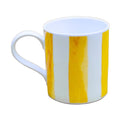 A white ceramic mug with two vertical yellow watercolor stripes, set against a solid beige background.