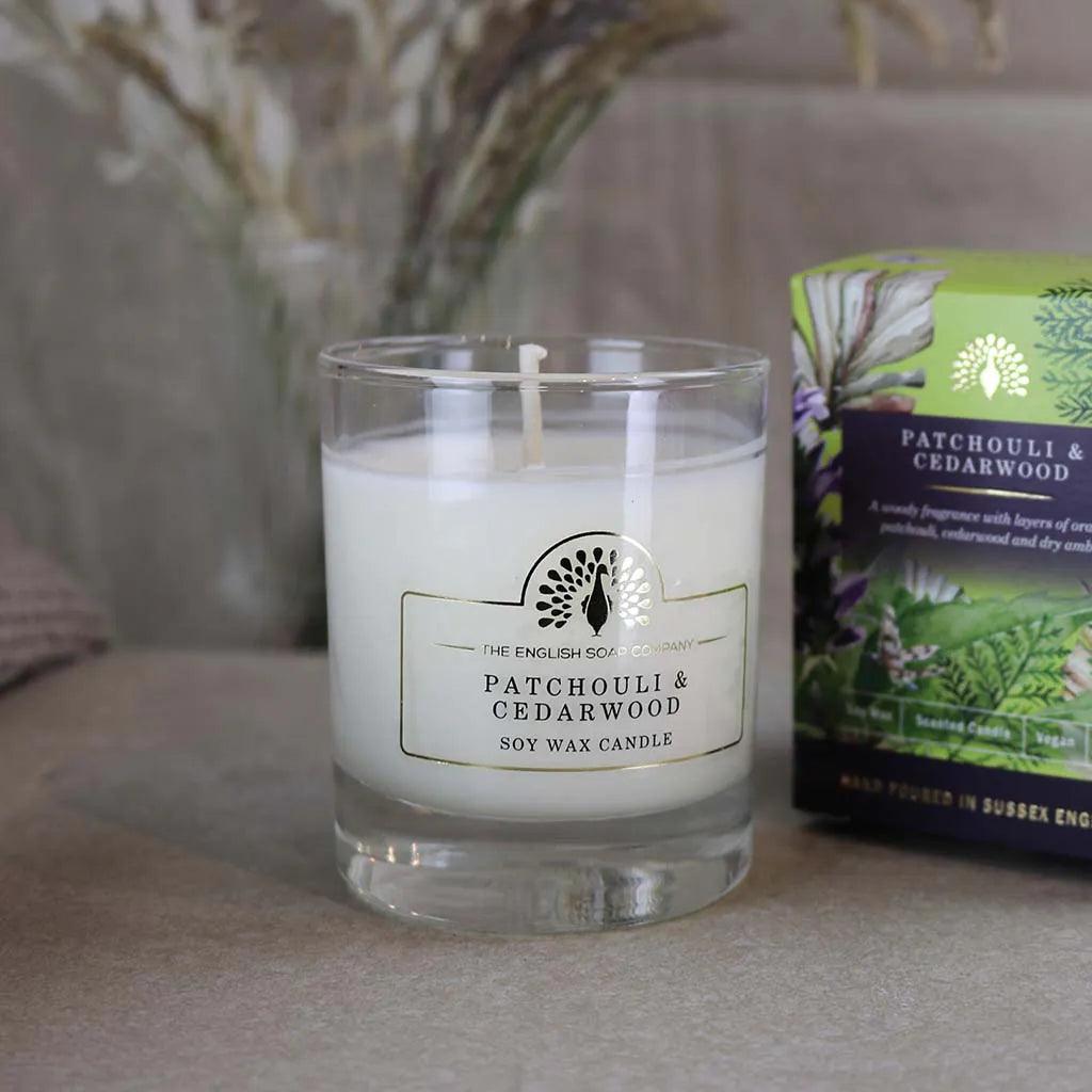 Candle with a label on a surface next to a box, with a blurred background - The Fig House