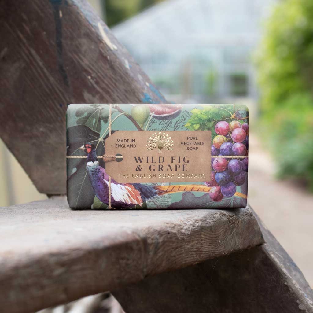 Bar of soap with 'Wild Fig & Grape' packaging on a wooden surface outdoors