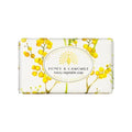A rectangular bar of soap wrapped in white paper featuring a yellow floral pattern and a central white oval label that reads 'HONEY & CAMOMILE luxury vegetable soap MADE IN ENGLAND' by The English Soap Company.