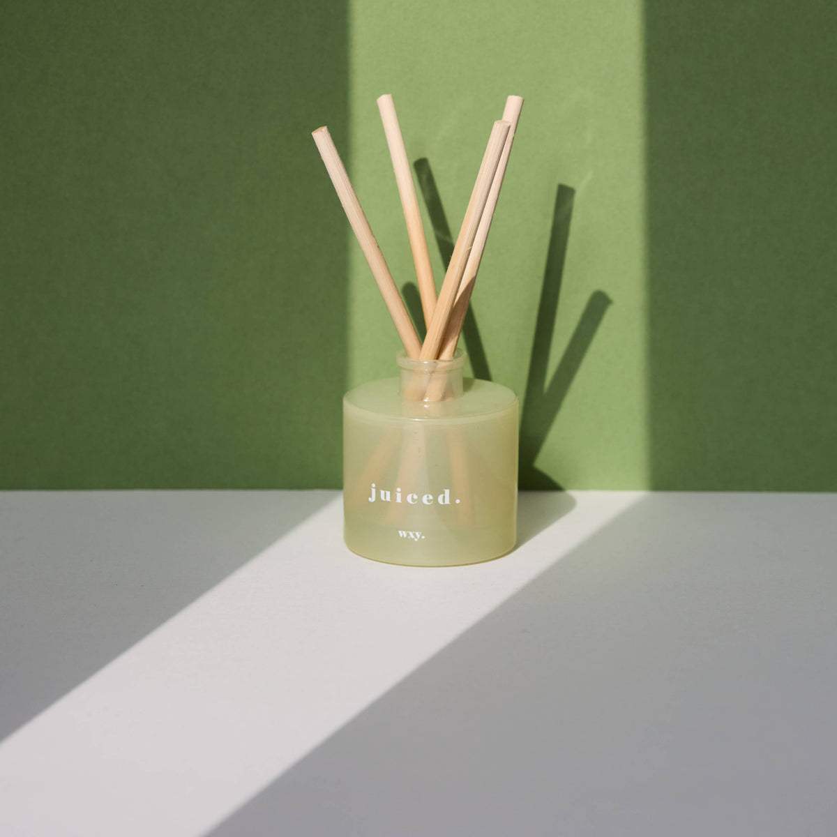 Green diffuser with wooden sticks on a green and gray background