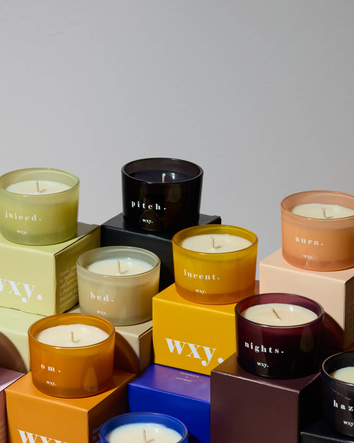Assorted candles with visible brand names on a gray background