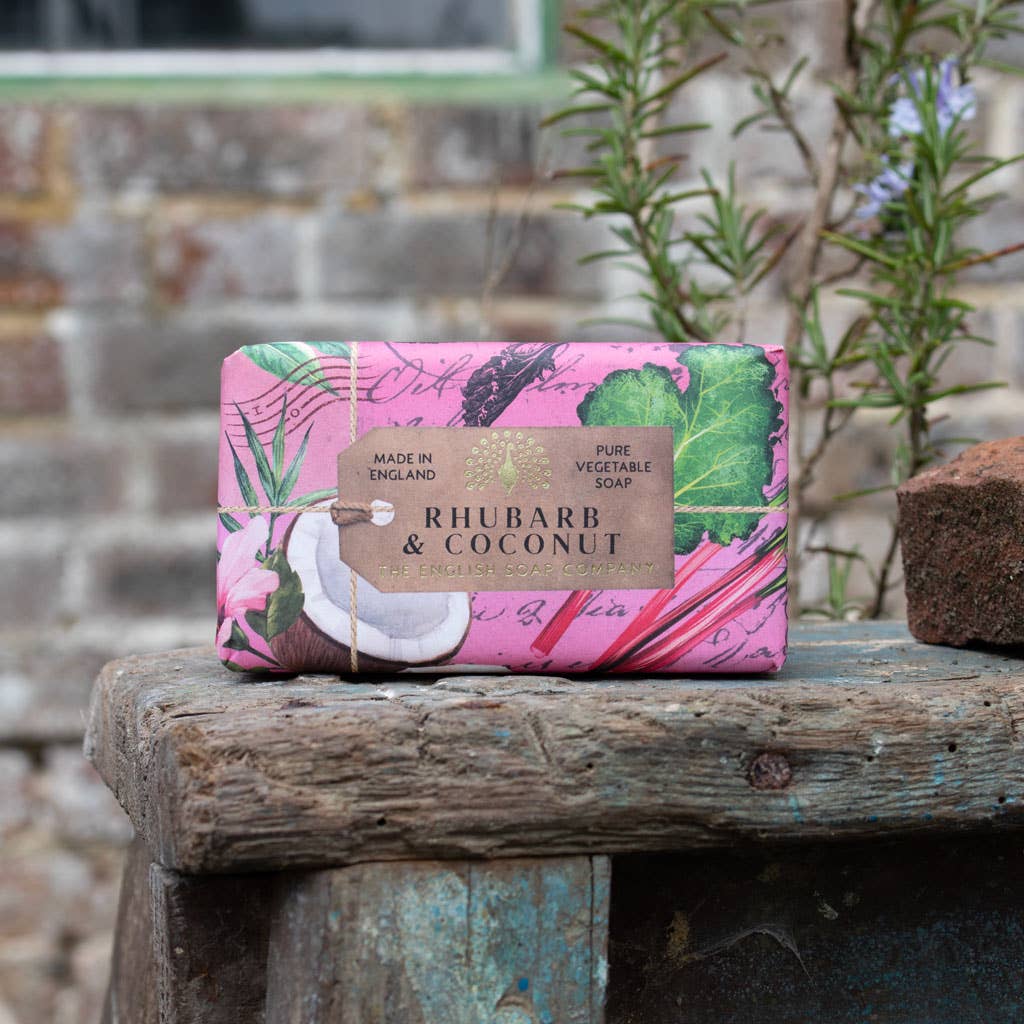 Bar of soap with a pink and green label on a wooden surface outdoors.
