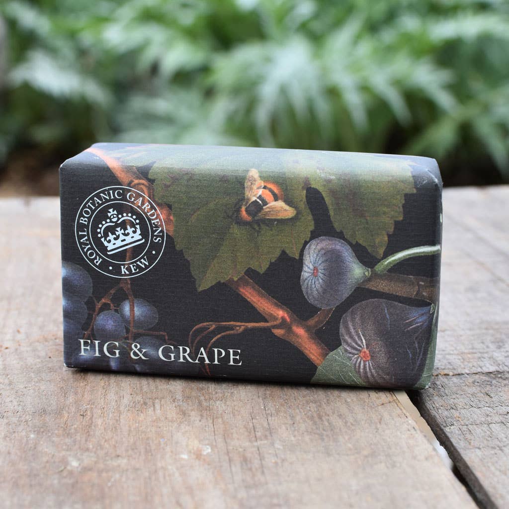 Bar of soap with 'Fig & Grape' design on a wooden surface with greenery in the background - The Fig House