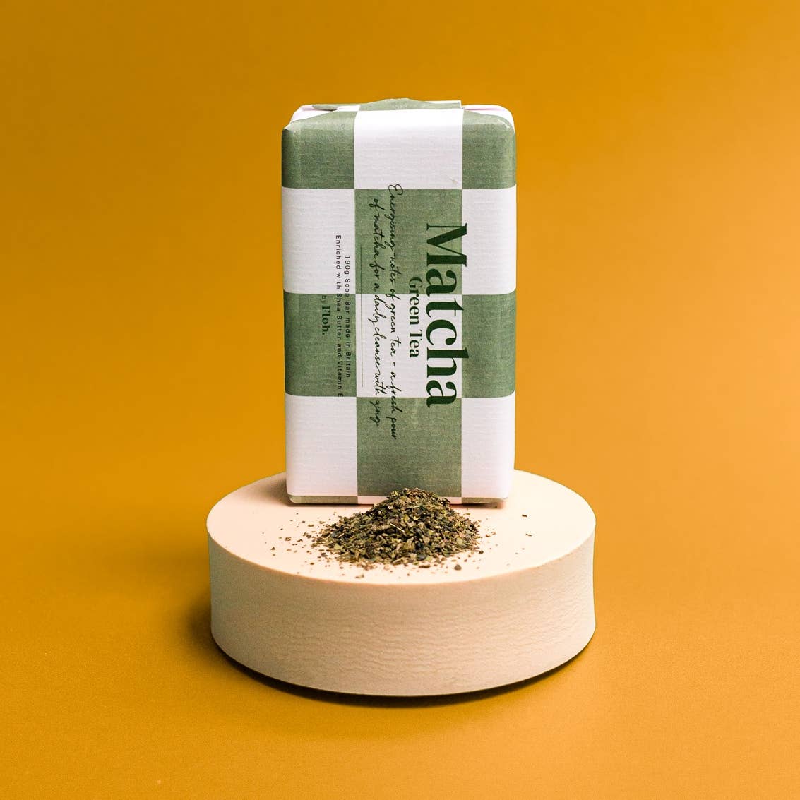 Matcha green tea packaging on a wooden stand with a yellow background