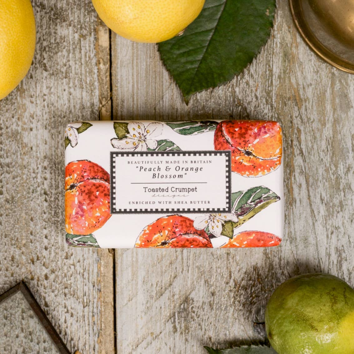 Bar of soap with decorative packaging featuring fruits on a wooden surface.