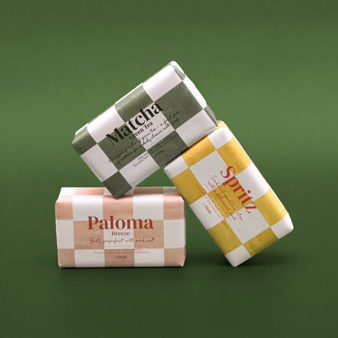 Three soap bars with checkered packaging on a green background