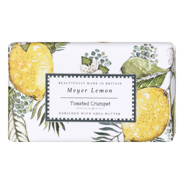 A rectangular bar of Meyer Lemon Toasted Crumpet soap, featuring a white background decorated with yellow lemons and green botanical leaves. A central white label with a black border displays the text 'Meyer Lemon Toasted Crumpet enriched with Shea Butter'.